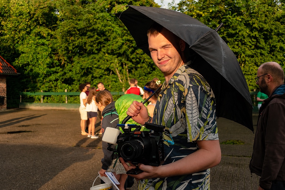 Matthijs Visser op een draaidag, met camera in de hand onder een paraplu in avondzon